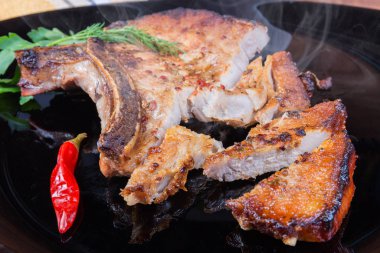 Kızarmış domuz filetosu. Tabakta kemik kırıntısı, kısmen kesilmiş.