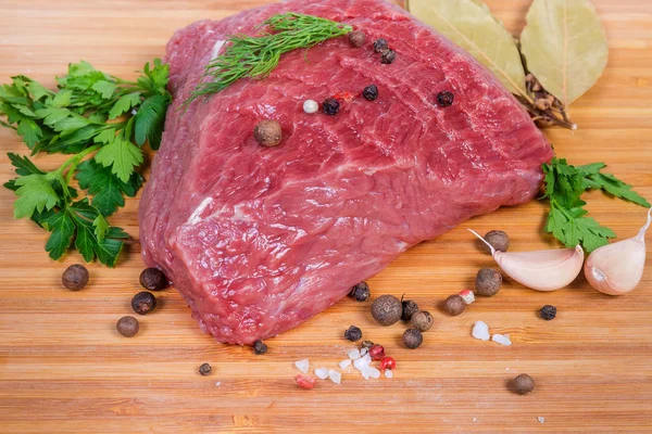 Trozo de carne cruda entre verduras y especias de cerca —  Fotos de Stock