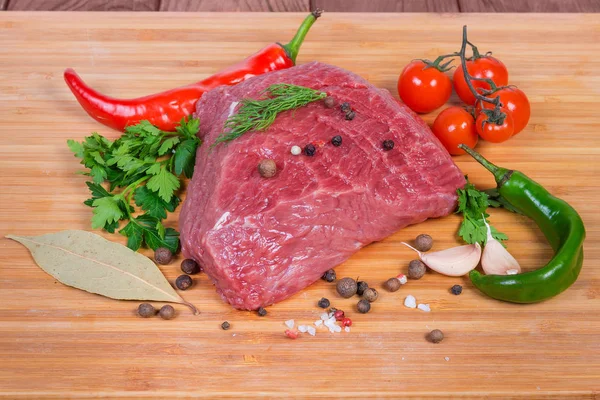 Kawałek niegotowanej wołowiny wśród warzyw, warzyw i przypraw — Zdjęcie stockowe
