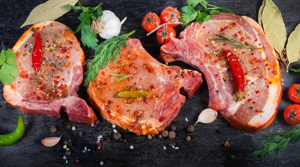 Trozos de lomo de cerdo en vinagre sin cocer, especias, verduras en la superficie negra — Foto de Stock