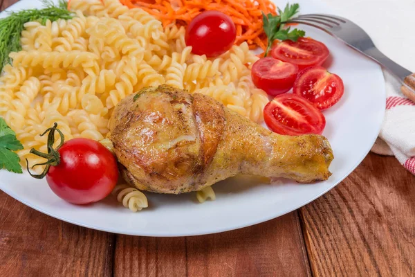 Τηγανητό πόδι κοτόπουλου κατά μαγειρεμένα σπειροειδή ζυμαρικά, λαχανικά, κοντινό πλάνο — Φωτογραφία Αρχείου