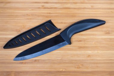Black kitchen ceramic knife and blade protector on cutting board clipart