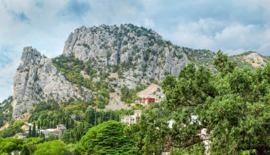 Kayalık dağ sıraları ve deniz kenarındaki köy ayaklarının altında.
