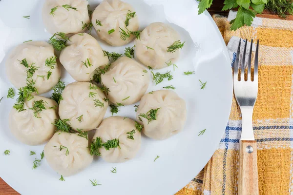 Boiled khinkali with chopped dill on dish, fragment top view — Stock Photo, Image