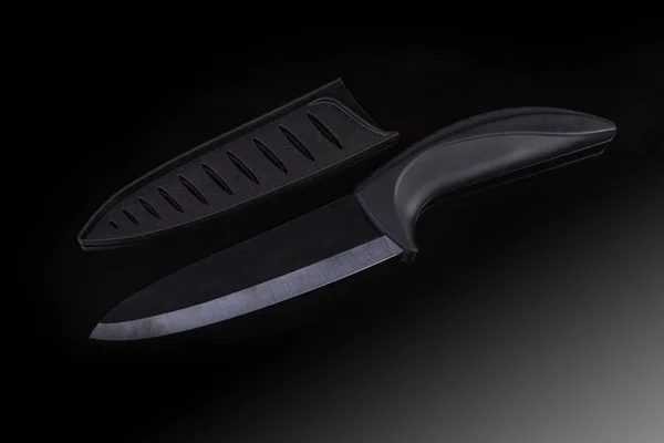 Black kitchen ceramic knife and blade protector on dark surface