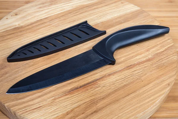 Cuchillo de cerámica de cocina negro y protector de hoja en el tablero de servir —  Fotos de Stock