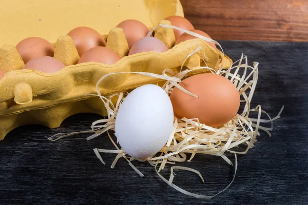 Bílé a hnědé vejce proti papírovému tácu s vejci — Stock fotografie