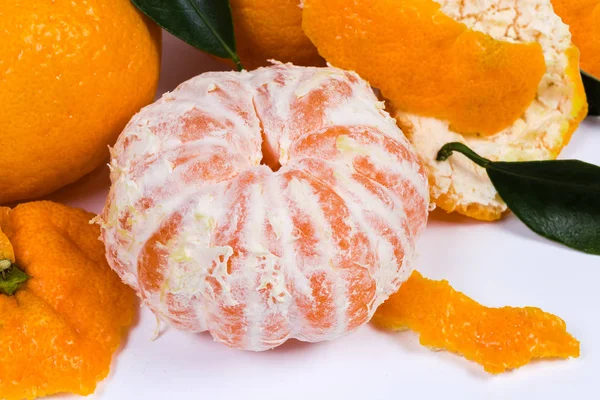 Peeled mandarin orange among the peel and other fruits close-up