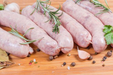 Ahşap kaplamalı baharatlar arasında pişmemiş domuz sosisi.