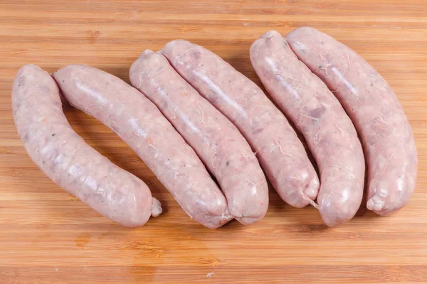 Uncooked pork sausages on wooden cutting board — Stock Photo, Image