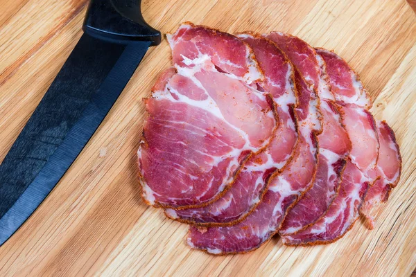 Ausgehärtete Schweinescheiben gegen Messer auf Schneidebrett in Nahaufnahme — Stockfoto