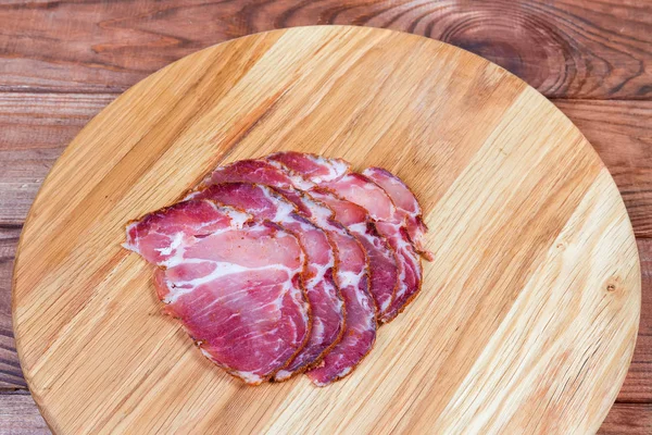 Gepökelte Schweinescheiben auf Holzschneidebrett auf rustikalem Tisch — Stockfoto