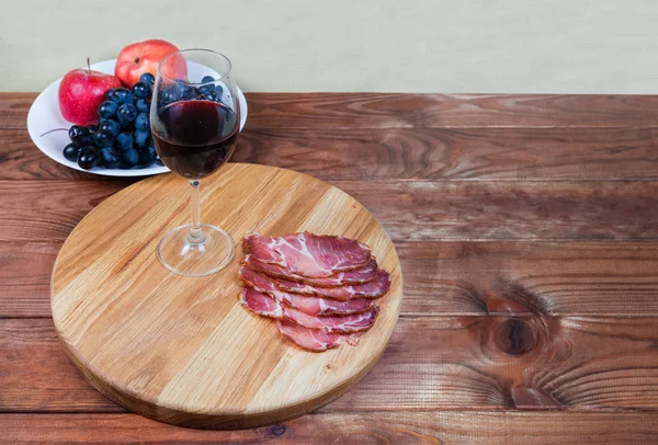 Red wine and cured pork slices on cutting board — Stock Photo, Image
