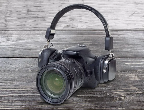 Headphones dressed on the digital camera on old wooden surface — 스톡 사진