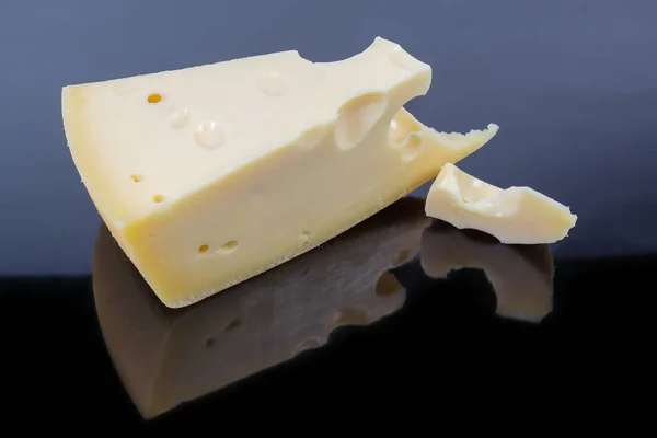 Swiss-type cheese on a dark reflective surface — 스톡 사진