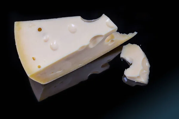 Swiss-type cheese on a dark reflective surface, top view — Stock Photo, Image