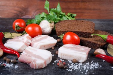 Pork belly slices, against the spices, vegetables, brown bread, selective focus