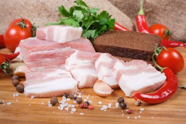 Partly sliced pork belly among spices, closeup in selective focus