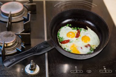 Eggs fried with green pea in frying pan on stove
