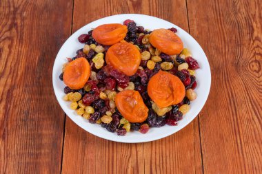 Different dried fruits and berries on dish on rustic table