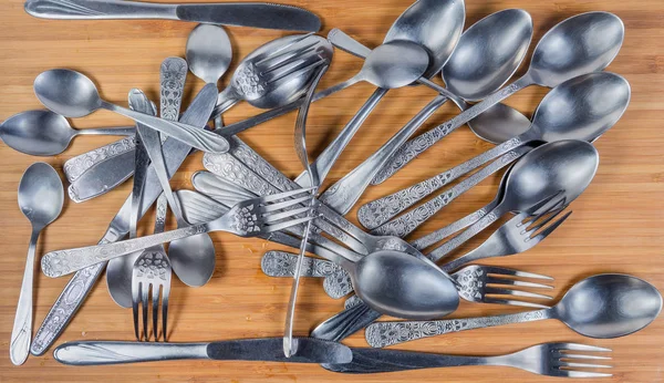 Stainless steel eating utensils on the wooden surface, top view