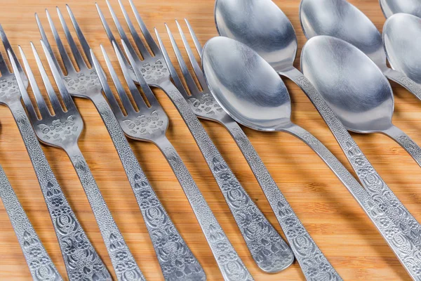 Spoons and forks laid on wooden surface, fragment close-up — Stock Photo, Image