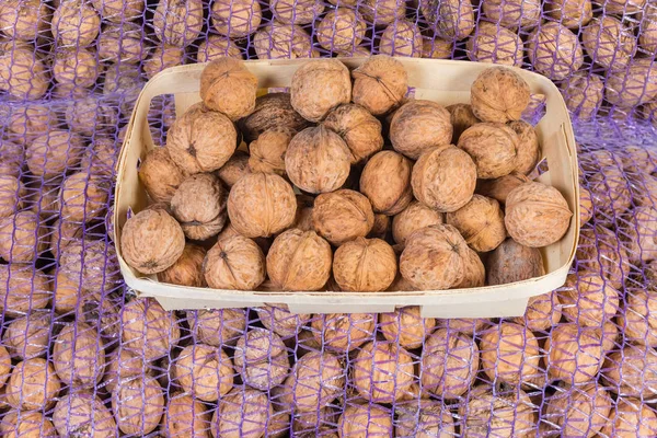 Walnuts in wooden basket on the mesh bags with nuts — Stock Photo, Image