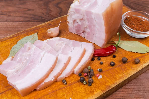 Aufgeschnittener gekochter Schweinebauch zwischen Gewürzen auf Schneidebrett — Stockfoto