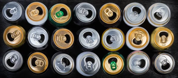 Vista superior de latas de bebidas abertas usadas em surafce preto — Fotografia de Stock