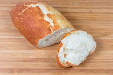 Tahta yüzeyde yarım ve bir dilim buğday ekmeği.