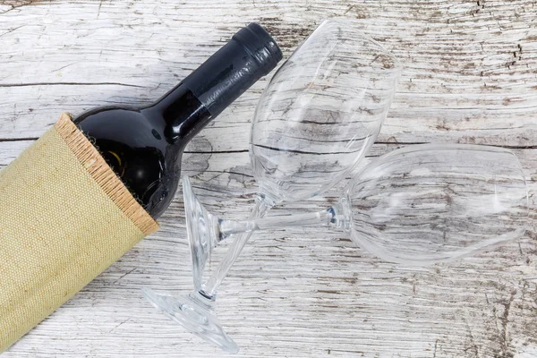 Μπουκαλάκι κόκκινο κρασί και άδεια ποτήρια σε παλιά ξύλινη επιφάνεια — Φωτογραφία Αρχείου
