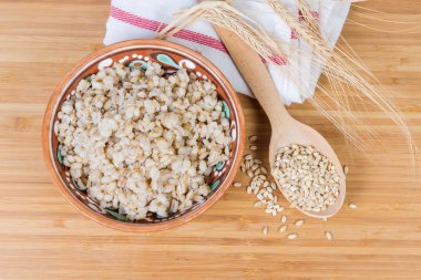 Pearl barley porridge, uncooked groats and barley ears, top view clipart