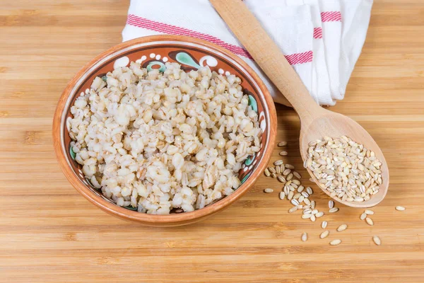 ボウルに真珠の大麦のお粥と調理されていない真珠の大麦の穀物 — ストック写真