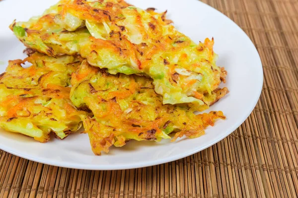 Smakelijke kool pannenkoeken op schotel op bamboe tafel mat closeup — Stockfoto