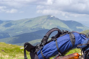 Mavi seyahat sırt çantası uzak dağların bulanık arka planında, seçici odak noktasında yakın plan şeklinde uzanır.