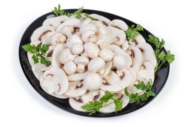 Dilimlenmiş ve tamamen taze, beyaz düğmeli mantarlar. Beyaz arka planda maydanoz dalları var.