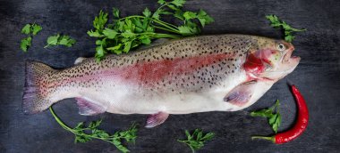 Taze pişmemiş gökkuşağı alabalığının tüm leşi kara yüzeydeki yeşillikler arasında