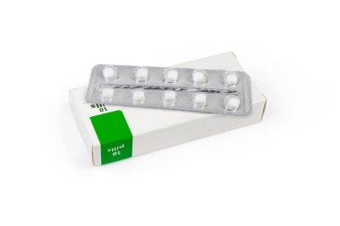 İlaç paketleri beyaz arka plandaki karton kutusunda yatıyor.