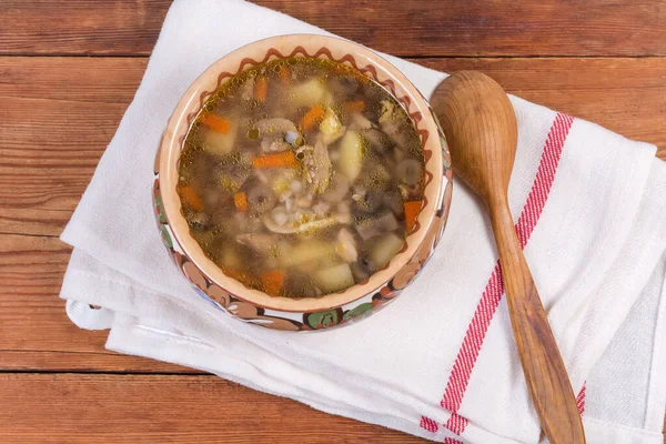 Buckwheat soup with mushrooms in the clay glazed bowl, wooden spoon on textile napkin on the rustic table, top view — Stock Image Buckwheat Soup Mushrooms Clay Glazed Bowl Wooden Spoon Textile Napkin Royalty Free Stock Images