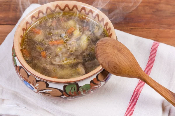 Freshly prepared buckwheat soup with mushrooms in the clay glazed bowl, wooden spoon on textile napkin on the rustic table close-up — Stock Image Freshly Prepared Buckwheat Soup Mushrooms Clay Glazed Bowl Wooden Spoon Stock Photo