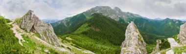 Kayalarla dolu Craggy Dağı kitlesi ve bir ön plandan geçiyor. Sarnia Kayası 'ndan Tatra Dağları' na uzanan Giewont dağının kuzey yamacının geniş panoramik manzarası