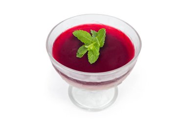 Kırmızı vişneli jelatin tatlı. Beyaz arka planda cam dondurma bardağında naneli yapraklarla süslenmiş.