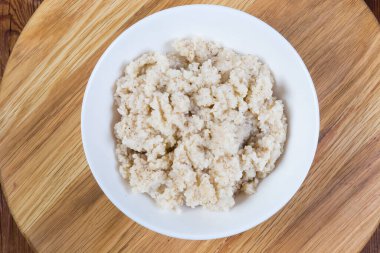 Tahta servis tahtasındaki beyaz kasede ezilmiş arpa ezmesinden yapılmış arpa lapası.