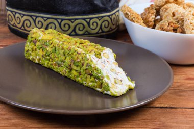 Kahverengi tabakta ezilmiş fıstıkla kaplı beyaz nougat çikolatası kırsal masadaki diğer doğu tatlılarına karşı.