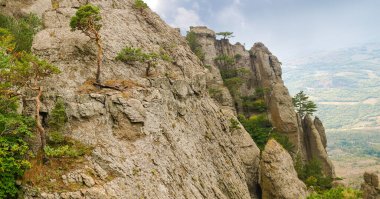 Uçurumlar ve kireçtaşlı dik yamaçlar vadideki tek ağaçlarla kaplı kayalar, panoramik manzara.