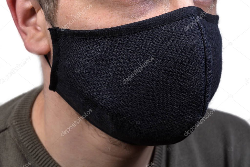 Black protective fabric mask with rubber bands wearing on a face close-up