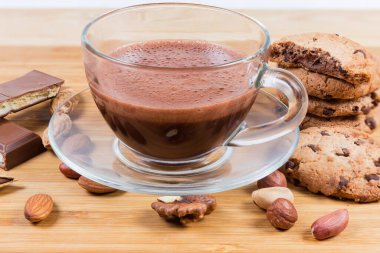 Çikolata parçalı kurabiyeler, çikolata parçaları ve çeşitli fındıklar arasında cam bardakta sıcak çikolata.
