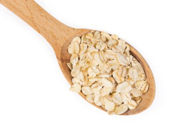 Beyaz arka planda, ahşap kaşıkta pişmemiş yulaf ezmesi, yakın plan.