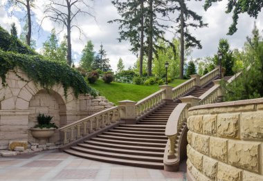 Stone staircase with carved stone railing in summer park, bottom view clipart