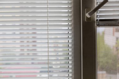 Pencerenin yatay Venedik jaluzileri ve dış termometresi olan parçası, seçici odak noktasında iç görünümü yakın plan. 